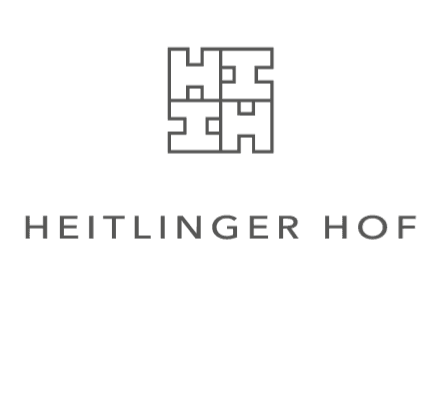 The image features a geometric black logo above the words HEITLINGER HOF in bold, uppercase letters on a white background, highlighting amenities like free loading stations for electric cars with pluq.